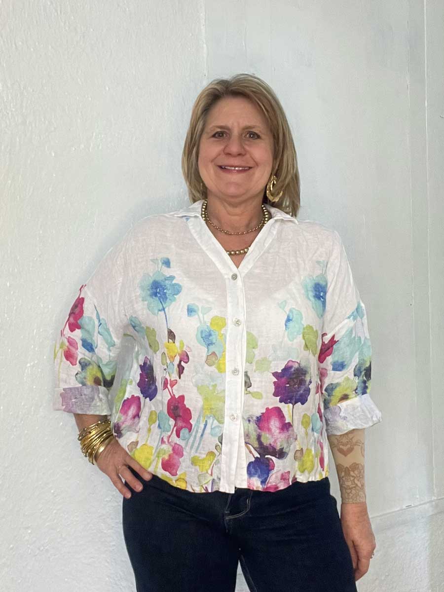 buttonup-watercolor-linen-top-white Lady showing floral detail on Italian linen top in white.